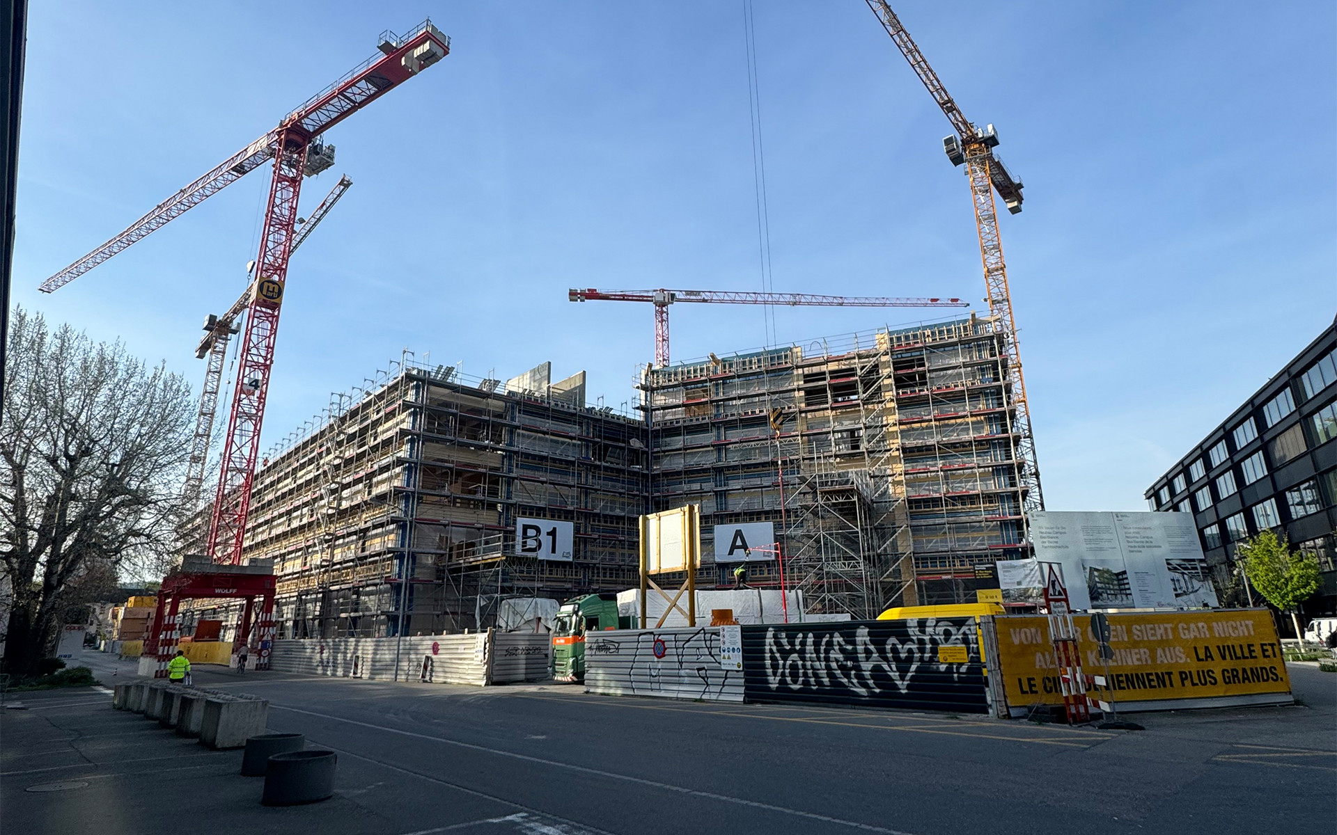 Large-scale construction site with cranes and multi-storey engineered timber building under assembly