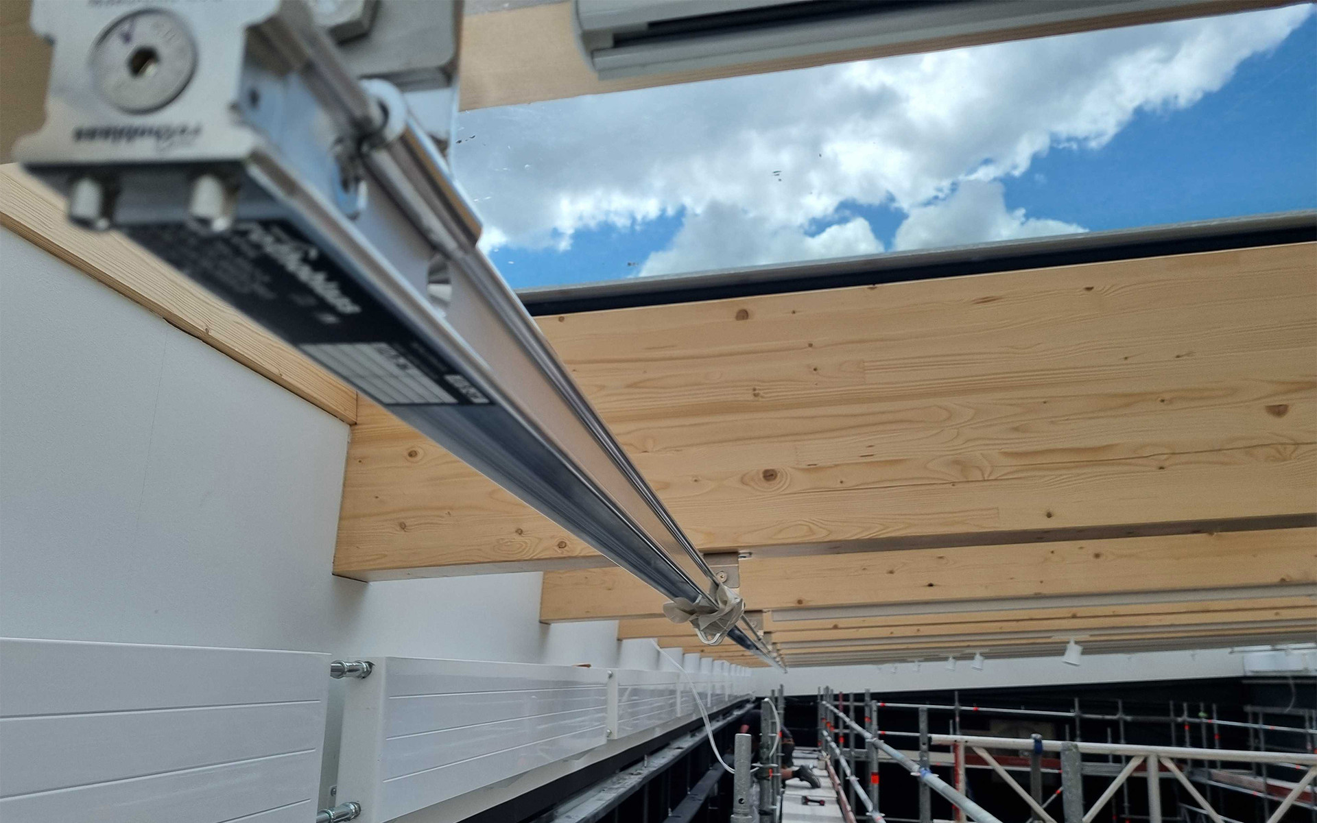  Rothoblaas H-RAIL horizontal lifeline system running along glulam timber beams of a large-span glazed timber roof during construction — Rebteknikeren ApS, Denmark.