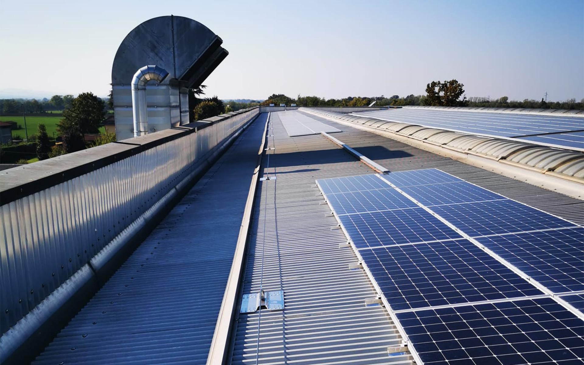 Industrial metal roof with solar panels and fall protection lifeline system.